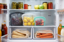 Open refrigerator with various food items including fruits, vegetables, and condiments.